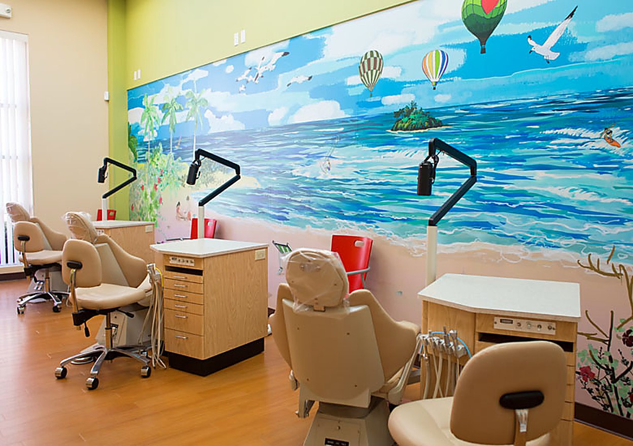 The open treatment bay with an ocean mural and four chairs